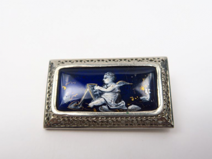 Broche en émail, à décor d'un amour peignant.  On y joint une chaine e
