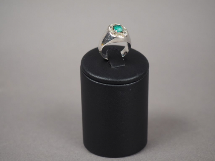 Bague chevalière en or blanc, ornée d'une émeraude entourée de roses. 