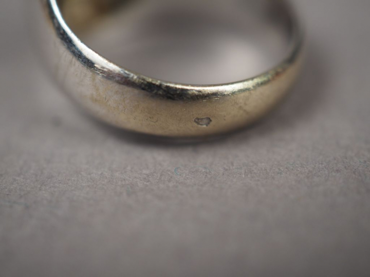 Bague chevalière en or blanc, ornée d'une émeraude entourée de roses. 