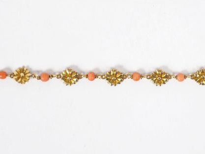 Bracelet en or jaune et perles de corail, à décor de fleurs.  Long. 14