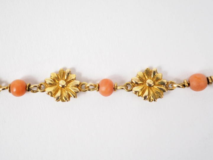 Bracelet en or jaune et perles de corail, à décor de fleurs.  Long. 14