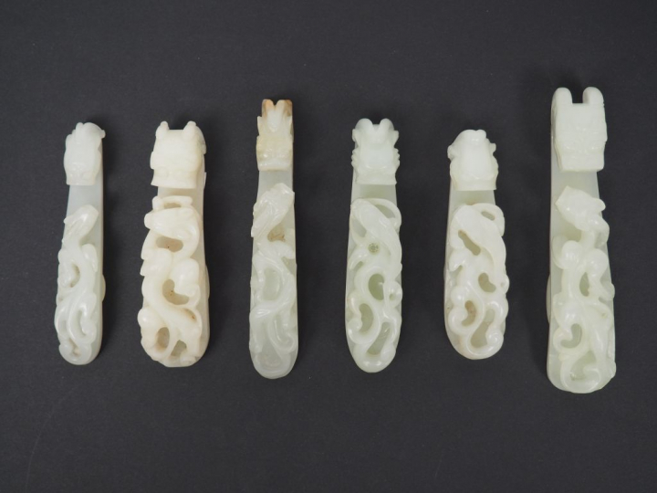 Ensemble de six fibules en jade blanc céladon décor de double dragon. 