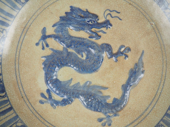 Plat en céramique émaillée beige et bleu, à décor en relief d'un drago