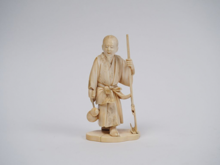 Okimono en ivoire représentant un maraicher tenant un instrument arrat