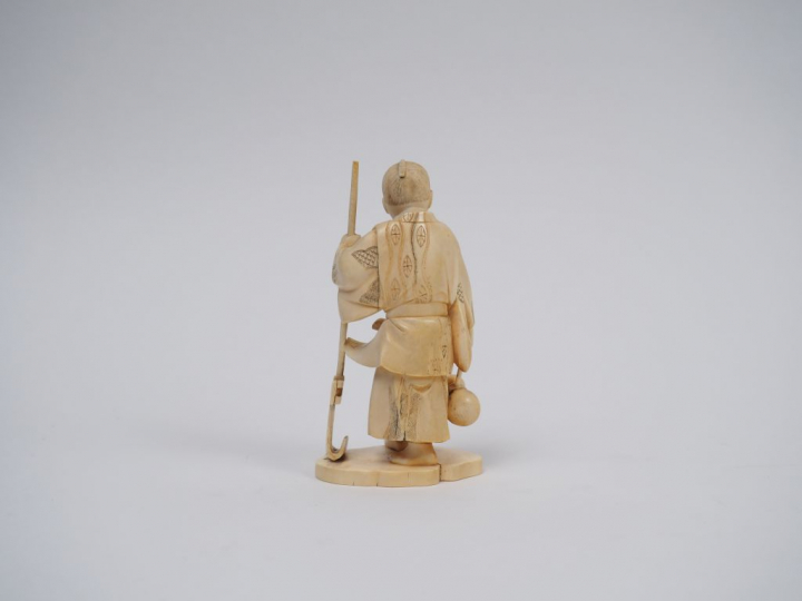Okimono en ivoire représentant un maraicher tenant un instrument arrat
