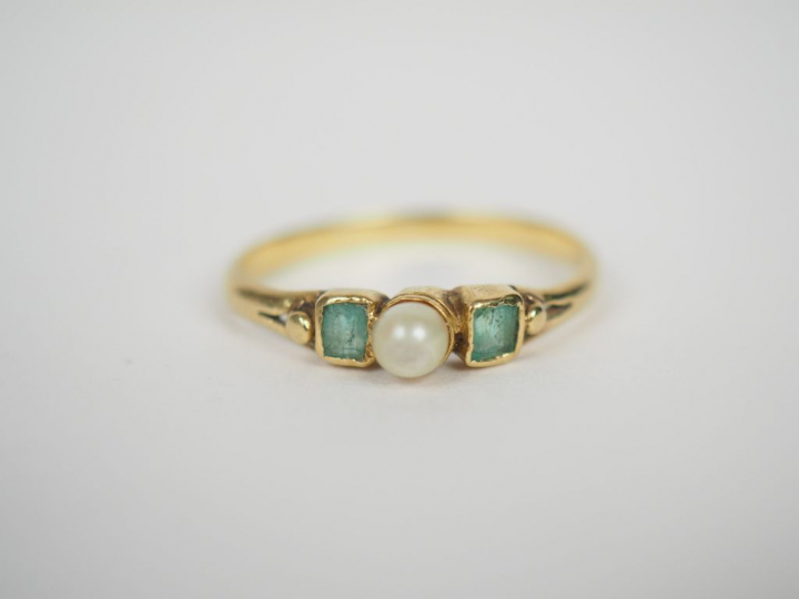 Bague en or jaune, ornée de deux pierres vertes et d'une perle.  TDD. 