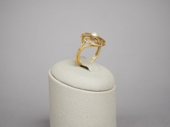 Bague en or jaune, à décor d'étoiles et d'une perle en son centre. TDD