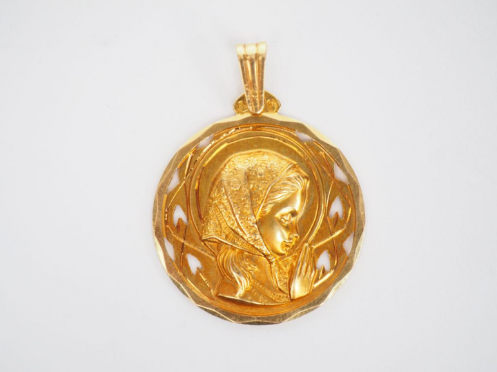 Médaille religieuse en or jaune, figurant une jeune fille en prière.  