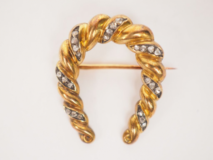 Petite broche en or jaune et diamants en forme de fer à cheval.  Poids