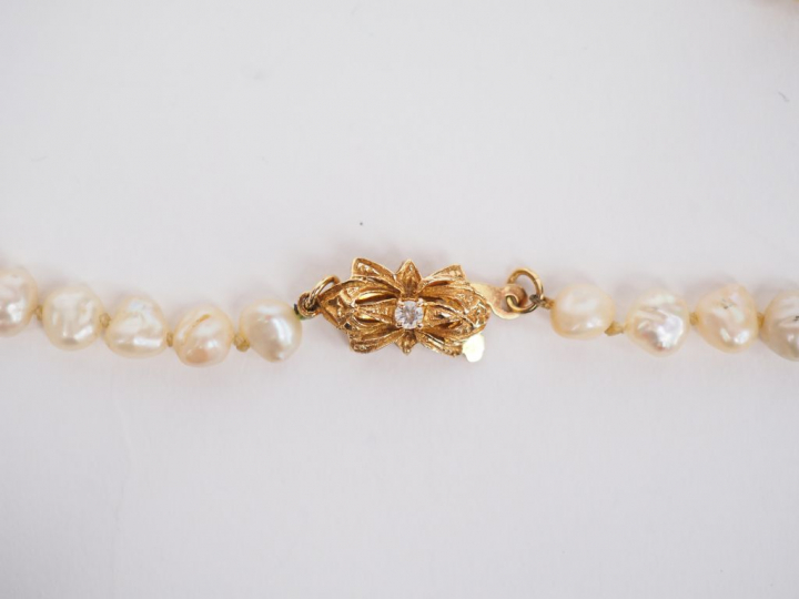 Collier de perles baroques.  Fermoir en métal doré, orné en son centre