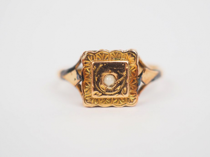 Bague carrée en or jaune, ornée en son centre d'une petite perle. TDD.