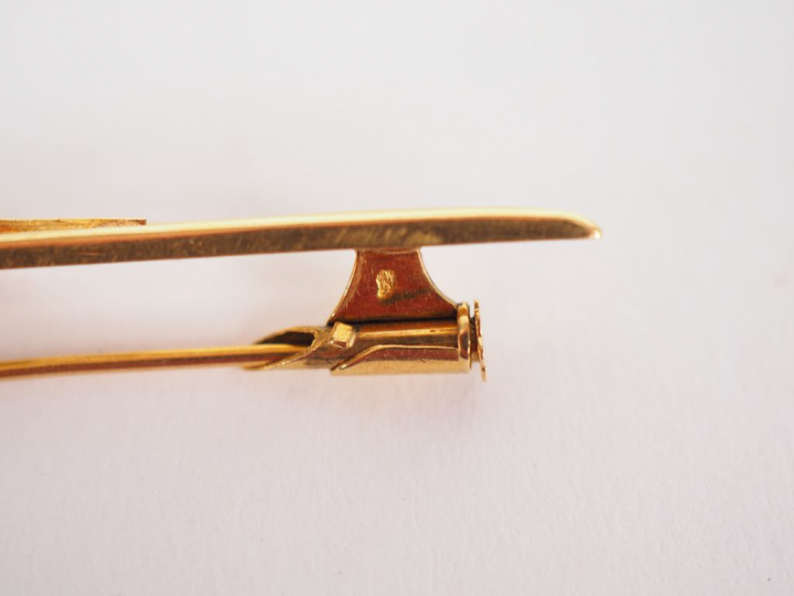 Broche barrette en or jaune, ornée en son centre d'une pierre bleue. L