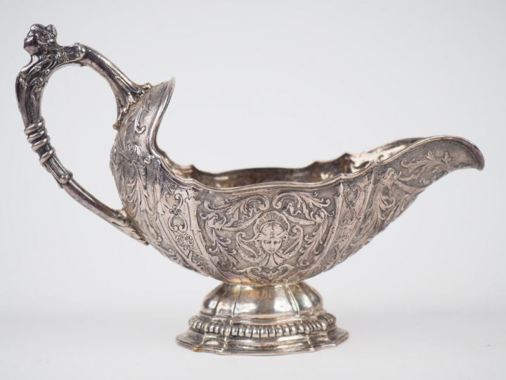 Saucière en argent étranger, à décor de masques et de rinceaux feuilla