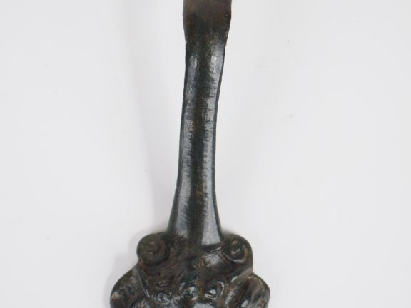 Anse en bronze avec un visage en médaillon. Epoque romaine. L. : 16 cm