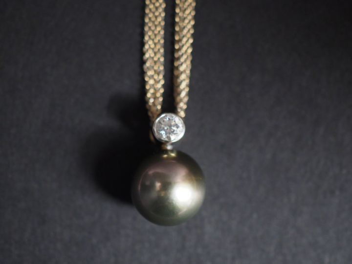 Pendentif en or blanc, à décor de perle grise surmontée d'un petit dia