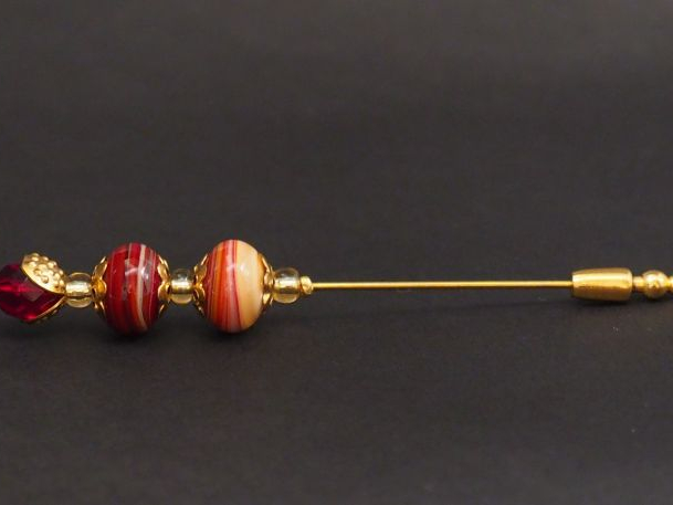 Epingle à cravate en métal doré et pierres dures.