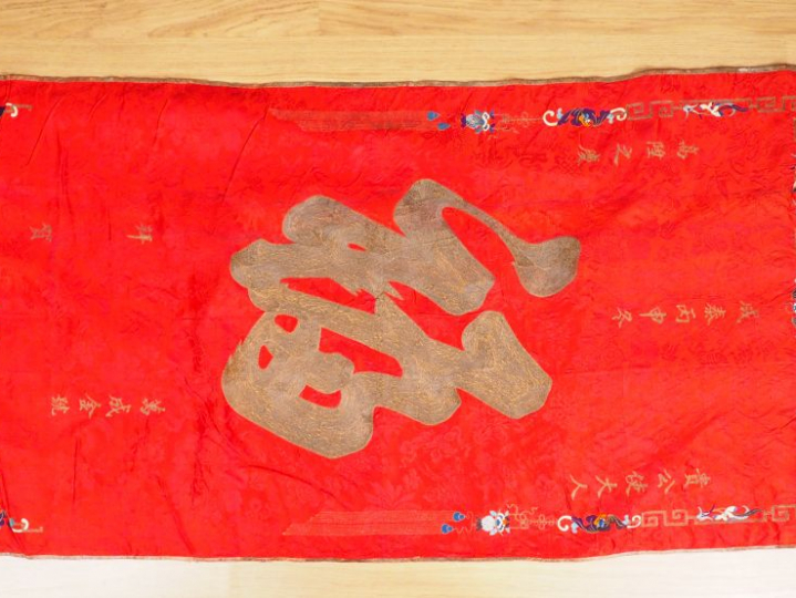 Grand panneau en soie rouge brodé aux fils polychromes et anciennement