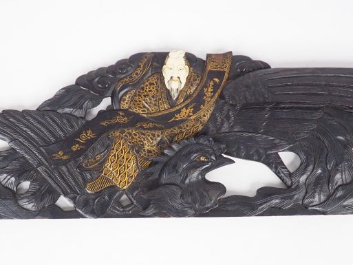 Corniche en bois sombre, sur lequel est assis un personnage aux vêteme