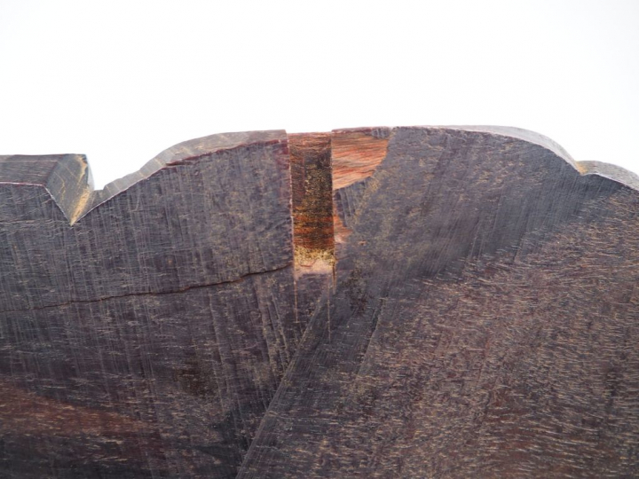 Corniche en bois sombre, sur lequel est assis un personnage aux vêteme
