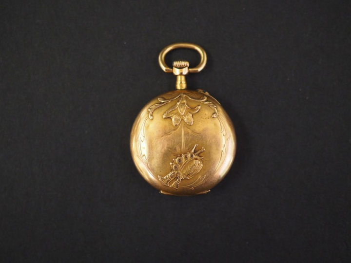 Petite montre de col en or jaune.  Le revers, à décor de trophée d'ins