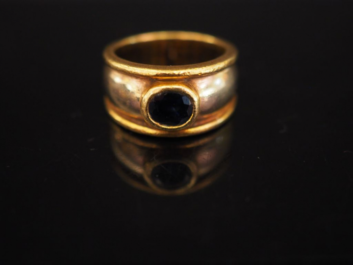 Bague deux tons d'or, ornée d'une pierre bleue en serti clos.  TDD. 45