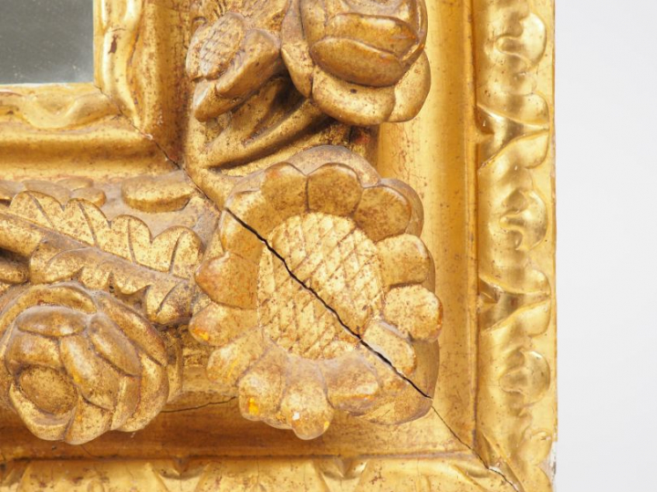 Miroir dans un cadre XVIIIème en bois et stuc doré à décor de fleurs e