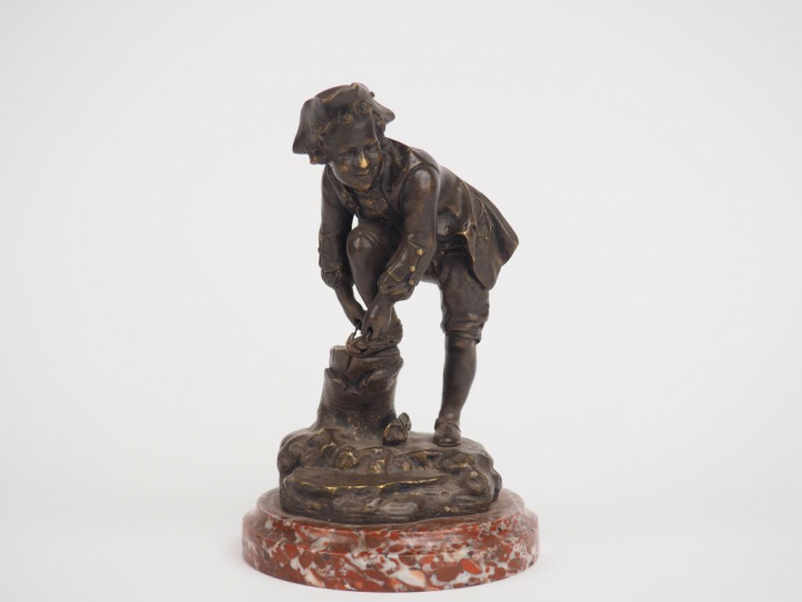 Petit sujet en bronze à patine brune "Jeune homme chaussant ses patins