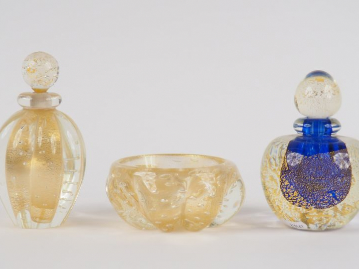 Deux différents flacons et un cendrier en verre pailleté d'or.