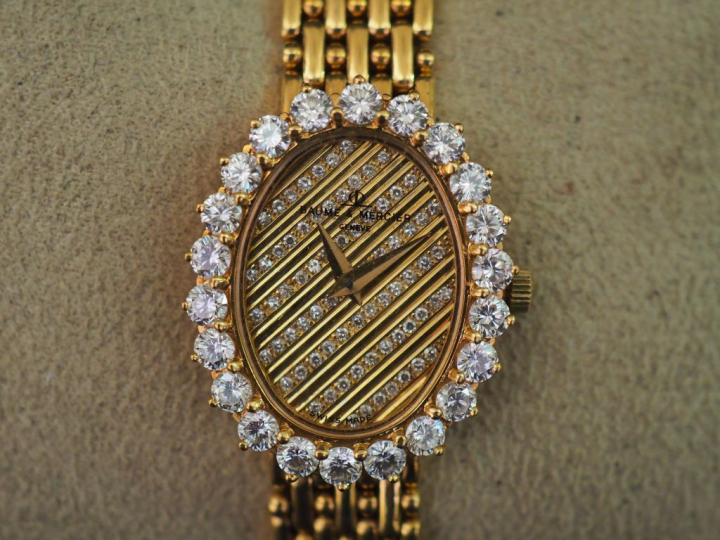 BAUME ET MERCIER. Montre de dame en or, cadran entouré de 22 diamants,
