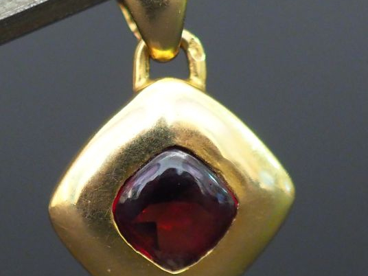 Petit pendentif en or en forme de losange orné d'une pierre rouge. Poi