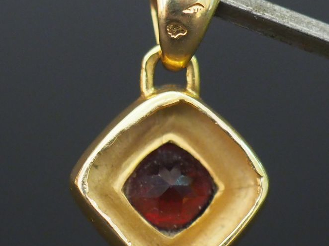 Petit pendentif en or en forme de losange orné d'une pierre rouge. Poi