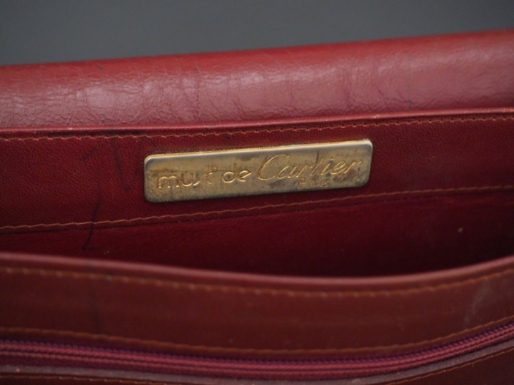 MUST DE CARTIER. Pochette en cuir marron H. 21 cm (état d'usage)  on y