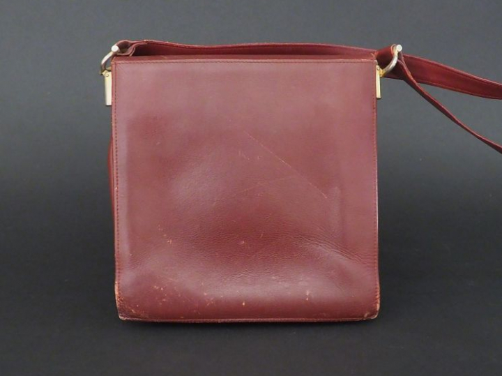MUST DE CARTIER. Pochette en cuir marron H. 21 cm (état d'usage)  on y