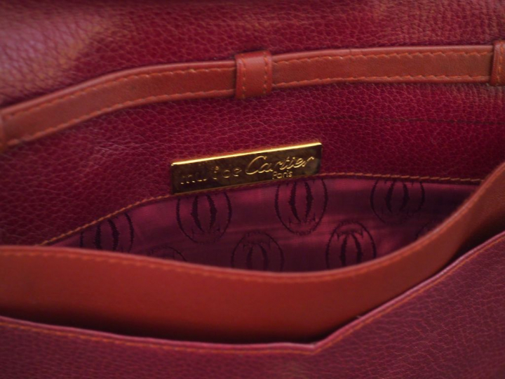 MUST DE CARTIER. Pochette en cuir marron H. 19 cm