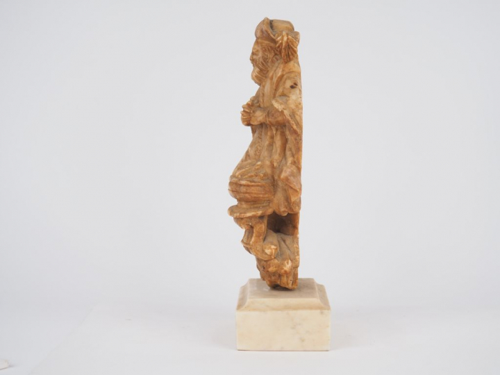 Allégorie de l’Hiver en albâtre sculpté en applique. Coiffé d’un chape