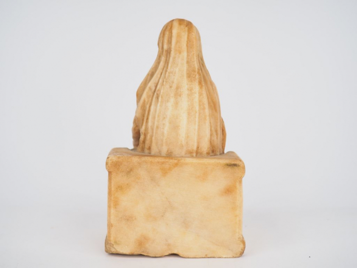 Vierge en albâtre sculpté en ronde-bosse. Assise sur un banc-trône orn