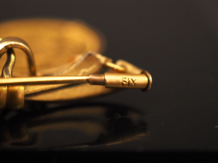 Broche en forme de noeud de ruban en plaqué or, ornée d’une pièce de 2