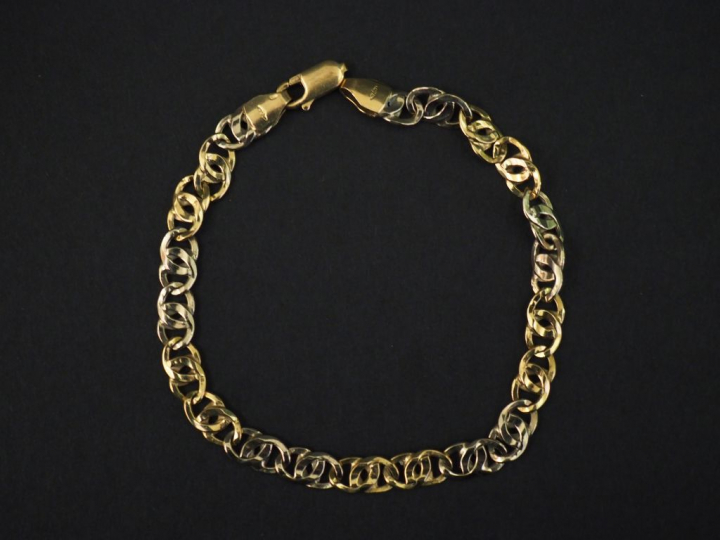 Bracelet articulé deux tons d’or, à décor de maillons entrelacés. Long