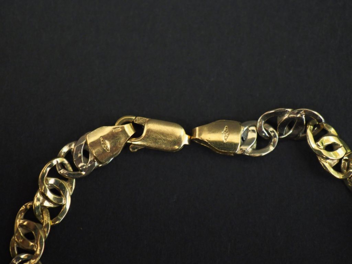 Bracelet articulé deux tons d’or, à décor de maillons entrelacés. Long