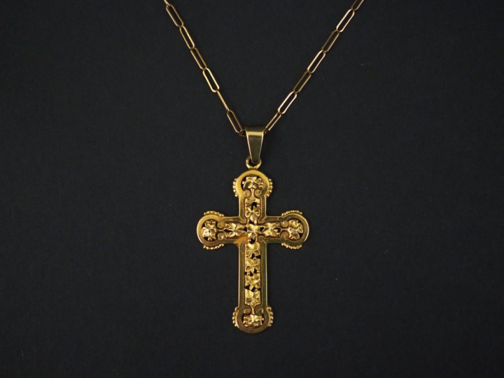 Pendentif en or jaune en forme de croix, à décor ajouré de feuilles.  
