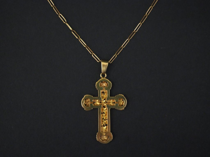 Pendentif en or jaune en forme de croix, à décor ajouré de feuilles.  
