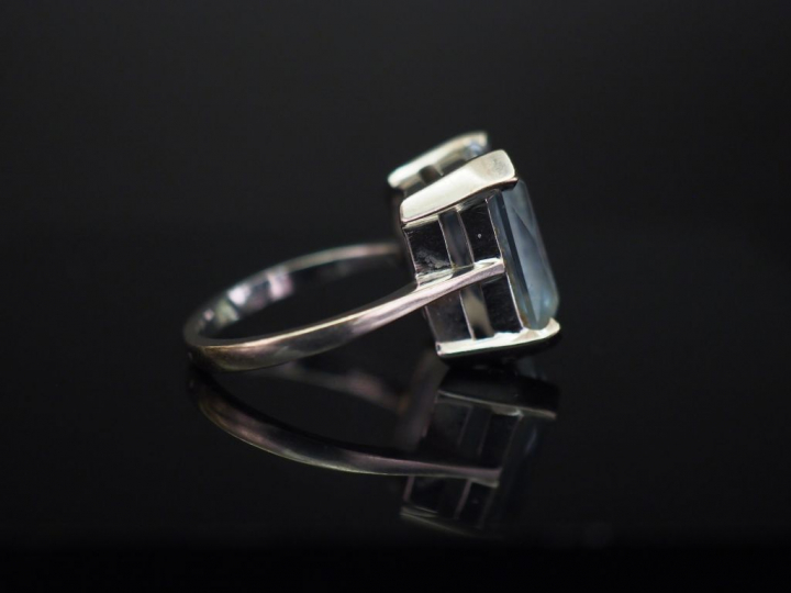 	Bague en or banc, sertie en son centre d’une pierre bleue. TDD. 52 Po