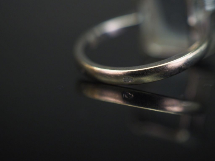 	Bague en or banc, sertie en son centre d’une pierre bleue. TDD. 52 Po