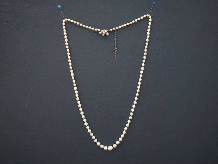 Collier de perles disposées en chute.  Fermoir en or blanc, en forme d