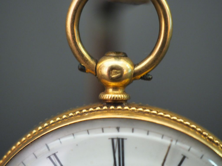 	Montre de col en or jaune. Le revers, à décor de médaillon feuillagé 