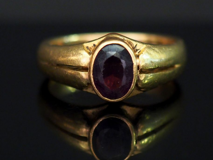 Bague jonc en or jaune, sertie en son centre d’une pierre rouge. TDD. 