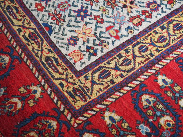 Grand tapis d'orient à fond clair et rouge. Dim. 570 x 310 cm.