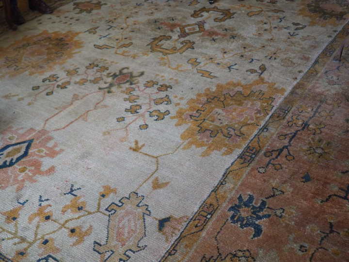 Grand tapis en laine à fond clair (mauvais état). Dim. 657 x 360 cm.
