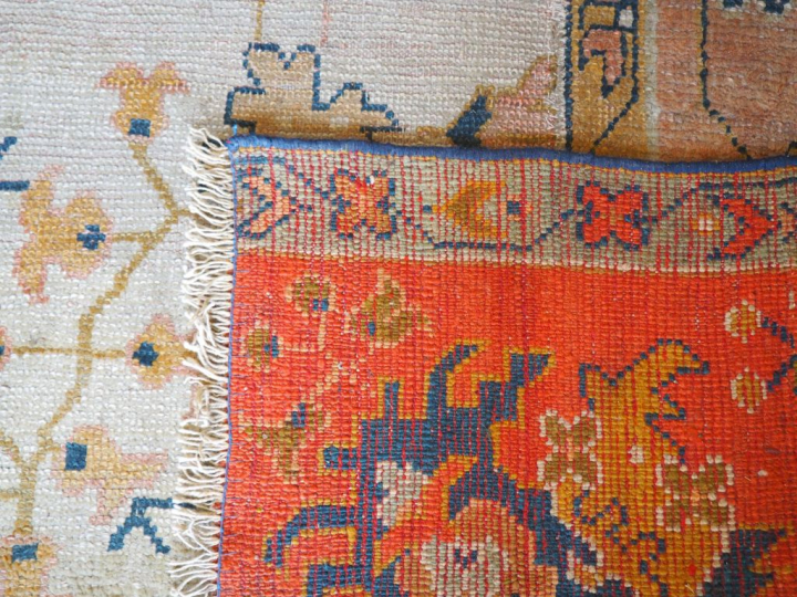 Grand tapis en laine à fond clair (mauvais état). Dim. 657 x 360 cm.