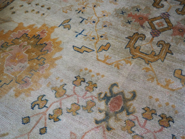 Grand tapis en laine à fond clair (mauvais état). Dim. 657 x 360 cm.